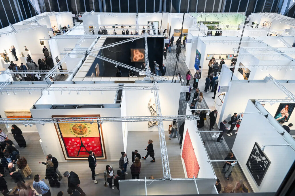An aerial photograph of booths at an art fair, with visitors walking the aisles.