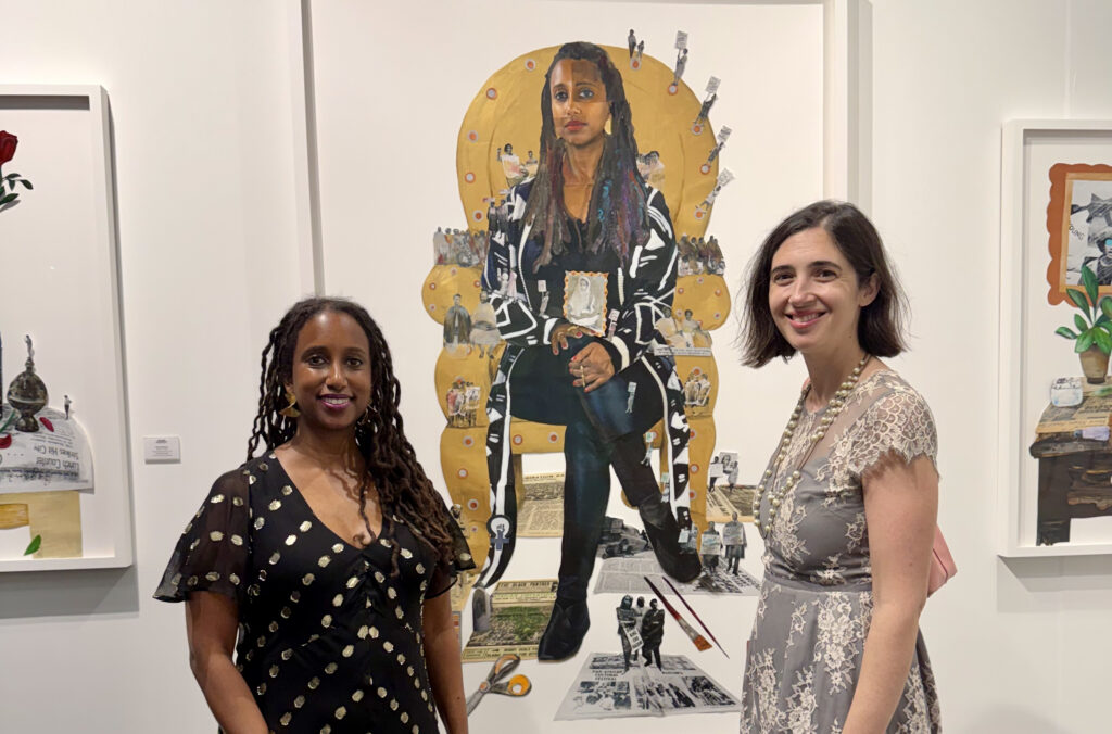 A photo of a young Black woman standing in front of a self portrait of herself seated in a golden throne. A young while woman with short dark hair stands next to her.