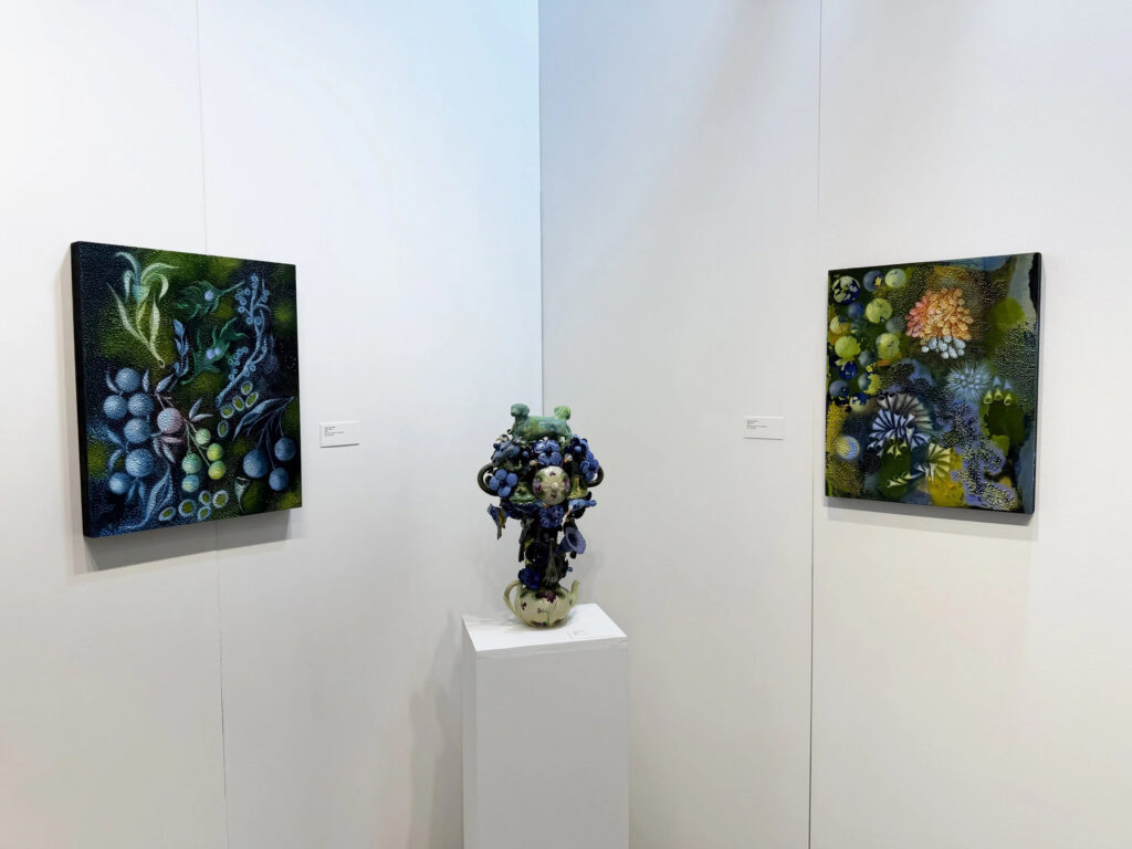 A photo of colorful paintings and ceramics on display at an art fair. 