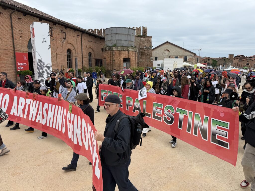 A photo of protesters carrying long pro-Palestine red banners.