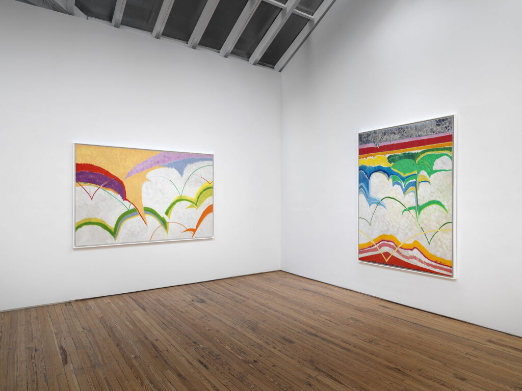 A photo of two colorful abstract paintings hanging in a white walled gallery.