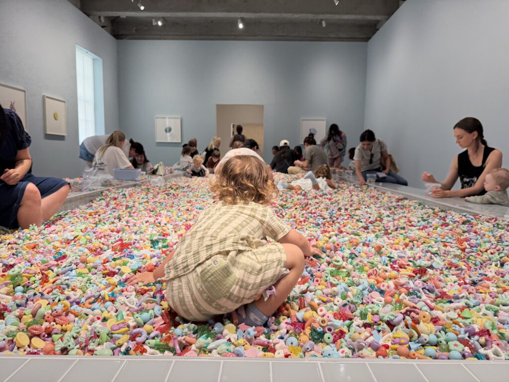A toddler crawling in a pit of colorful plastic beads.