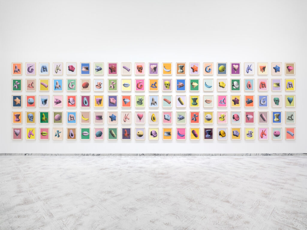A photo of a grid of colorful framed prints hanging in a white art gallery.