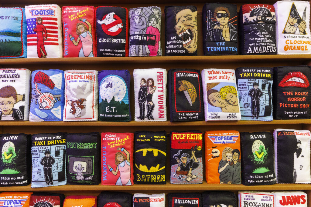 A photo of a display of sculptures made of felt of vintage VHS tapes.